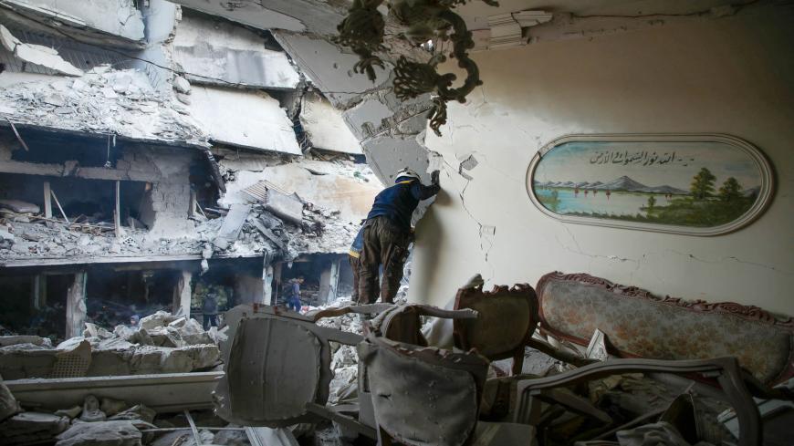 A member of the Syrian Civil Defense, also known as the White Helmets, searches through the rubble and debris in a building at the site of reported airstrikes on the rebel-held town of Ariha in the northern countryside of Idlib province, Syria, Jan. 30, 2020.