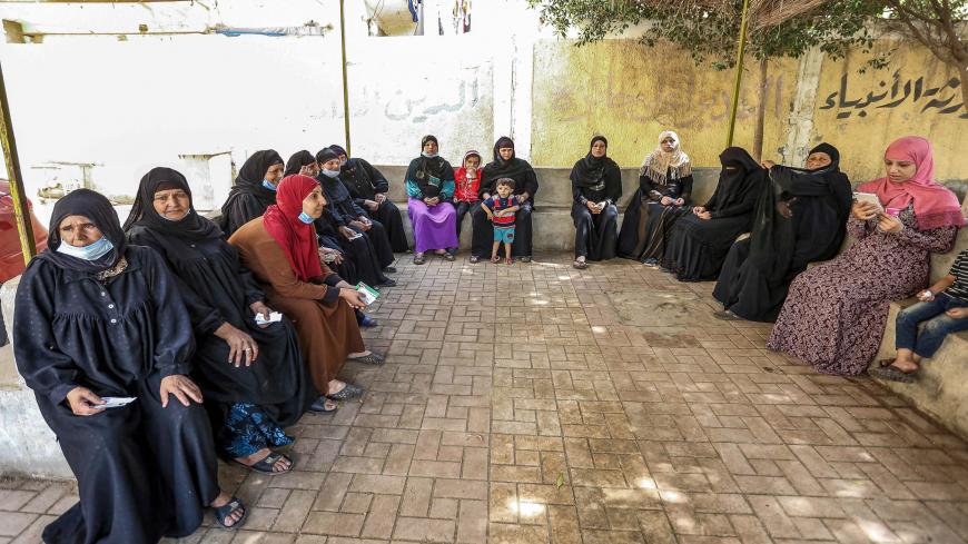 Female voters, some mask-clad due to the coronavirus pandemic, wait before entering a polling station in El-Ayyat, during the first stage of the lower house elections, south of Cairo, Egypt, Oct. 24, 2020.