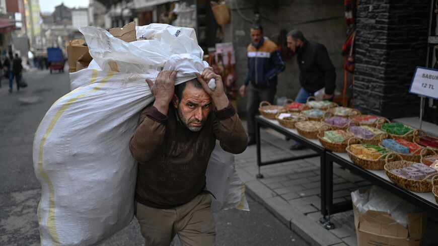 Worker carries sack of goods on back 