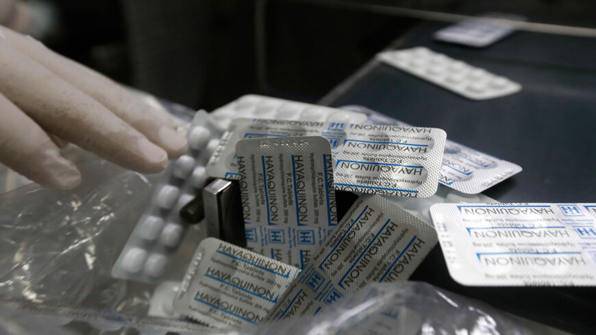 An employee of a Syrian pharmaceutical factory shows packs of the hydroxychloroquine drug in the government-controlled city of Homs, Syria, April 28, 2020.