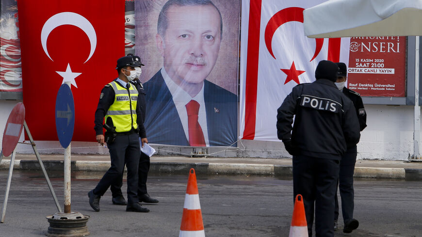 Turkish Cypriot police stand before a portrait of Turkish President Recep Tayyip Erdogan in the disputal coastal town of Varosha, in Famagusta, Cyprus, Nov. 15, 2020.