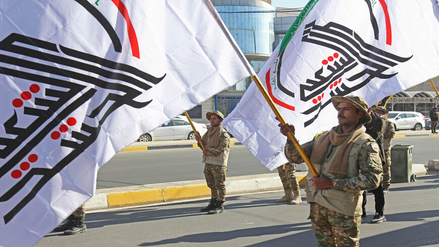 Members of the Popular Mobilization Units wave the faction flag during a symbolic funeral ceremony in the central holy city of Karbala, on the anniversary of the airstrikes by US planes on several bases belonging to the Hezbollah brigades near al-Qaim, Iraq, Dec. 29, 2020.