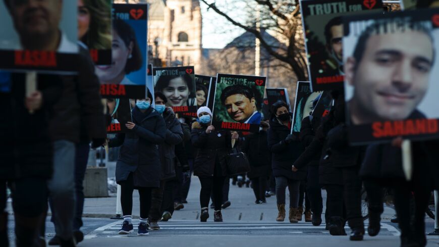 People hold signs with images of the victims of the downed Ukraine International Airlines flight PS752, which was shot down near Tehran by Iran's Islamic Revolutionary Guard Corps, as family and friends gather to take part in a march to mark the first anniversary, in Toronto, Ontario, Canada, on Jan. 8, 2021. Canada and other nations whose citizens died in the tragedy called on Tehran to come clean about the tragedy and "deliver justice" for the victims' families.