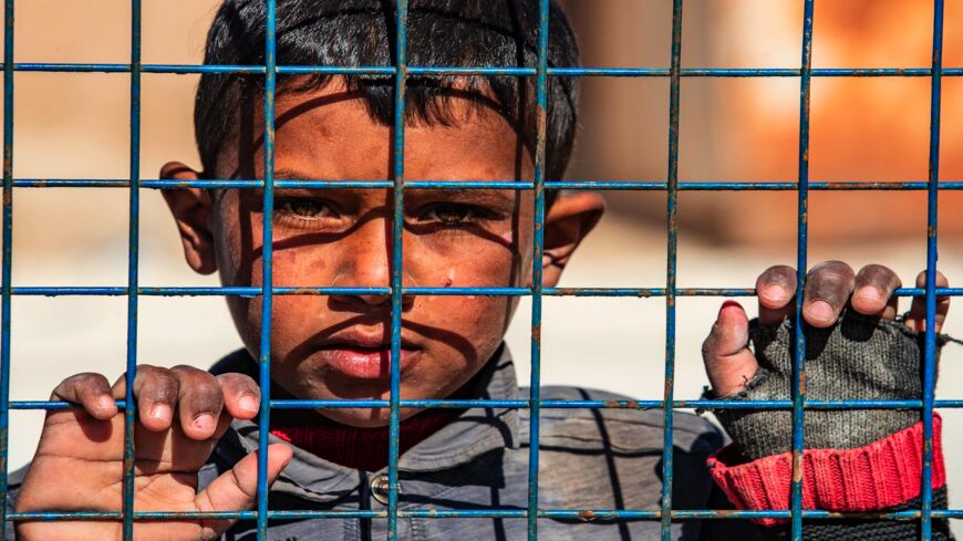 A boy awaits departure during the release of another group of Syrian families from the Kurdish-run al-Hol camp, which holds suspected relatives of Islamic State (IS) group fighters, in Hasakah governorate of northeastern Syria, on Feb. 20, 2021.