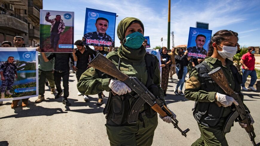 Female members of the Syrian Kurdish internal security services known as Asayish march in a procession ahead of the body of their fallen comrade Khalid Hajji, who was killed following clashes with pro-regime forces, during his funeral in Syria's northeastern city of Qamishli on April 22, 2021.