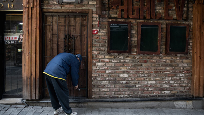 An employee of Agac Evi Blues Bar locks the bars front door after checking the inside after the venue has been closed for nearly a year due to coronavirus restrictions on February 24, 2021 in Istanbul, Turkey.