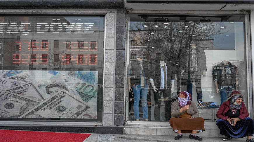 Women sit next to an exchange office at Laleli in Istanbul, Turkey, March 22, 2021.