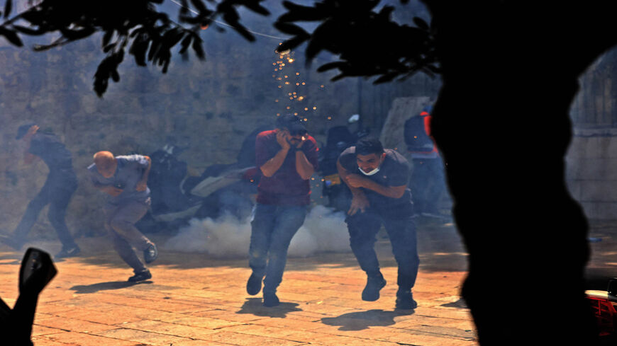 Palestinians run for cover from tear gas fired by Israeli security forces in the Old City, ahead of a planned march to commemorate Israel's takeover of Jerusalem in the 1967 Six-Day War, Jerusalem, May 10, 2021.