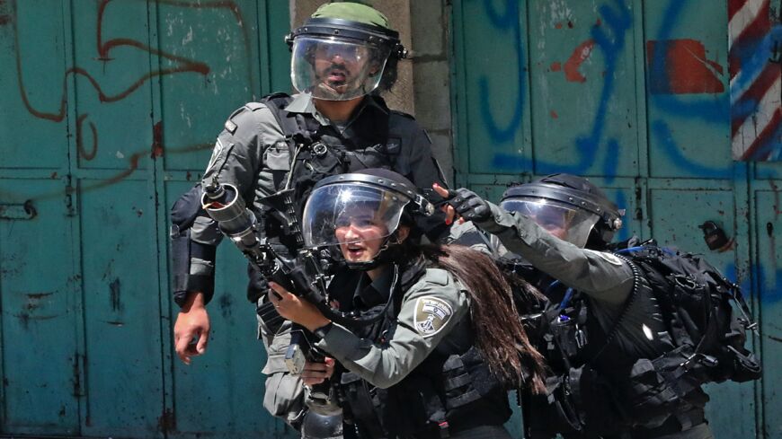 A member of the Israeli security forces fires tear gas at Palestinian protesters, during confrontations with them in the occupied West Bank city of Hebron, on May 14, 2021.