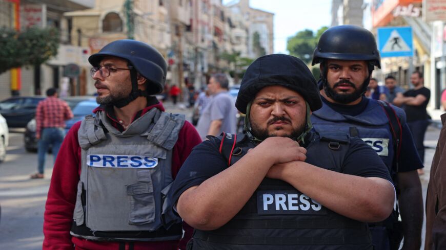 Palestinian journalists stand in shock following the destruction of Jala Tower, which was housing international press offices, by an Israeli airstrike in the Gaza Strip on May 15, 2021. The Israeli airstrike demolished the 13-floor building housing Qatar-based Al Jazeera television and American news agency The Associated Press in the Gaza Strip.