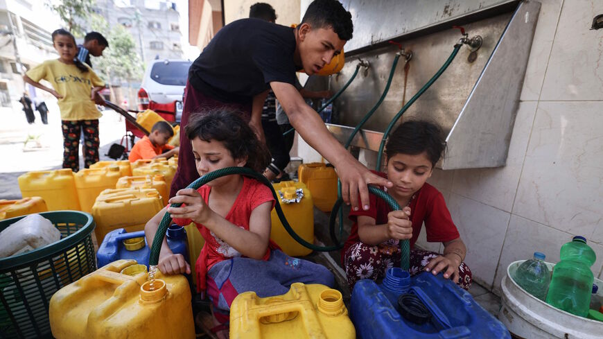 Palestinian children fill up gallons with water in Gaza City on May 20, 2021. 