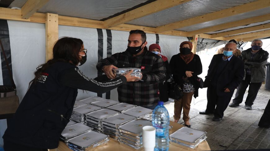 A volunteer gives out food handouts to people in need at the Lebanese grassroots organization in Beirut's Mar Mikhael district, which was hard hit by last year's port explosion, on March 24, 2021. 