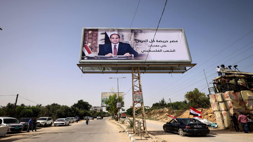 Palestinians wave Egyptian flags while sitting in a vehicle parked beneath a giant billboard depicting Egyptian President Abdel Fattah al-Sisi with a quote from him reading in Arabic "Egypt is extremely keen for all the rights of the Palestinian people," as they wait to receive the incoming Egyptian intelligence convoy entering the Gaza Strip on the Palestinian side of Erez border crossing with Israel near Beit Hanoun, May 31, 2021.