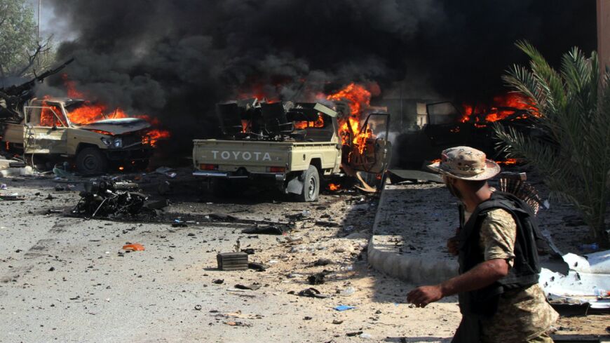 A fighter from the pro-government forces loyal to Libya's Government of National Unity looks at GNA forces' vehicles burning after a suicide bomber of the Islamic State detonated his explosives close to a group of soldiers on Aug. 16, 2016, in an area of central Sirte known as District Two.