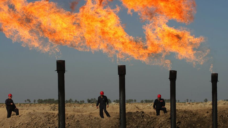 Iraqi workers walk at the Halfaya oil field near the southern city of Amara on Dec. 12, 2009.