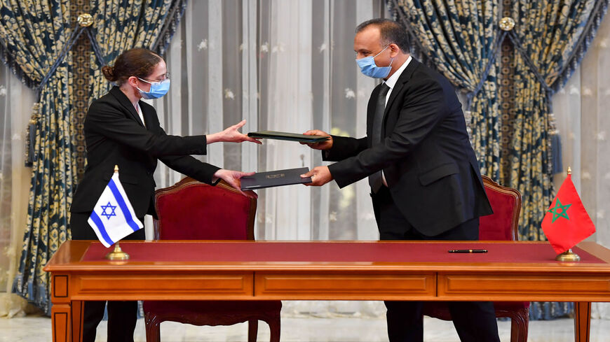 Chief economist at Israel's Ministry of Finance Shira Greenberg (L) and Morocco's Director General of the Customs and Indirect Tax Administration at the Ministry of Economy and Finance Nabil Lakhdar exchange a signed agreement on the first Israel-Morocco direct commercial flight at the Royal Palace, Rabat, Morocco, Dec. 22, 2020.