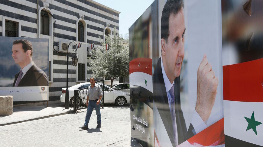 A Syrian man walks walks in between election campaign posters bearing portraits of Syrian President Bashar al-Assad, a candidate for the upcoming presidential election, in the capital Damascus on May 18, 2021.