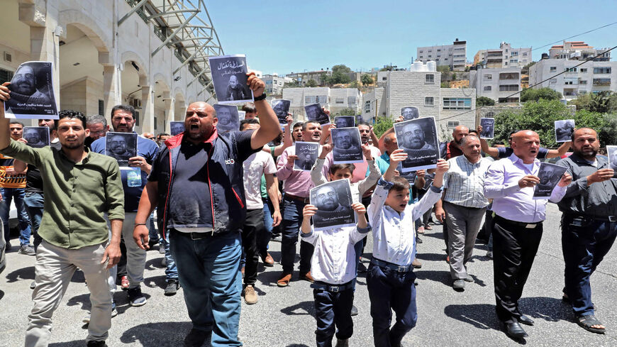 Demonstrators hold up images of Palestinian activist Nizar Banat, who died in late June during a violent arrest by Palestinian Authority security forces, as they march during a protest in the city of Hebron, West Bank, July 2, 2021.