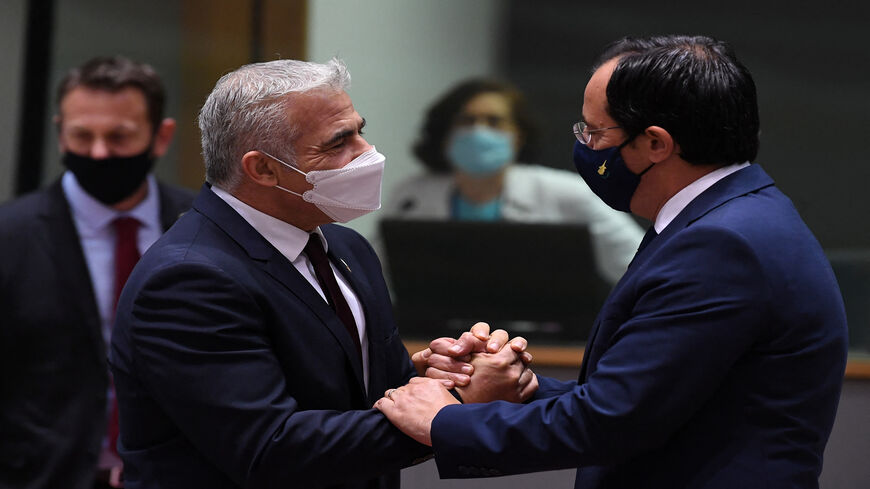 Israeli Foreign Minister Yair Lapid (L) talks with Cypriot Foreign Minister Nikos Christodoulides during a Foreign Affairs Council meeting at the EU headquarters, Brussels, Belgium, July 12, 2021.