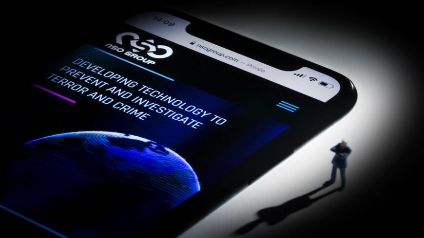 This studio photographic illustration shows a smartphone with the website of Israel's NSO Group.