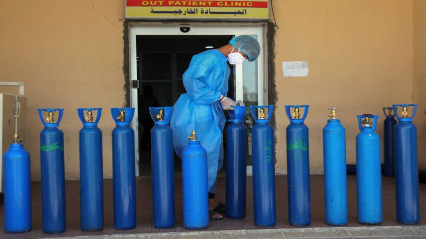 An Iraqi medic picks an oxygen bottle for a COVID-19 patient at a hospital in the northern Iraqi city of Dohuk.