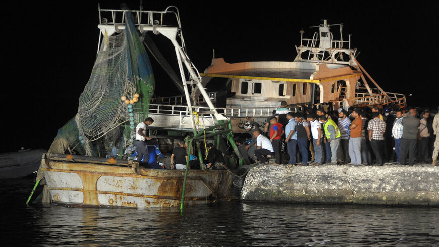 People gather on the quay as a wreck of a migrant boat raised by the Egyptian navy and maritime rescuers arrives in the Egyptian port city of Rosetta, Sept. 27, 2016.