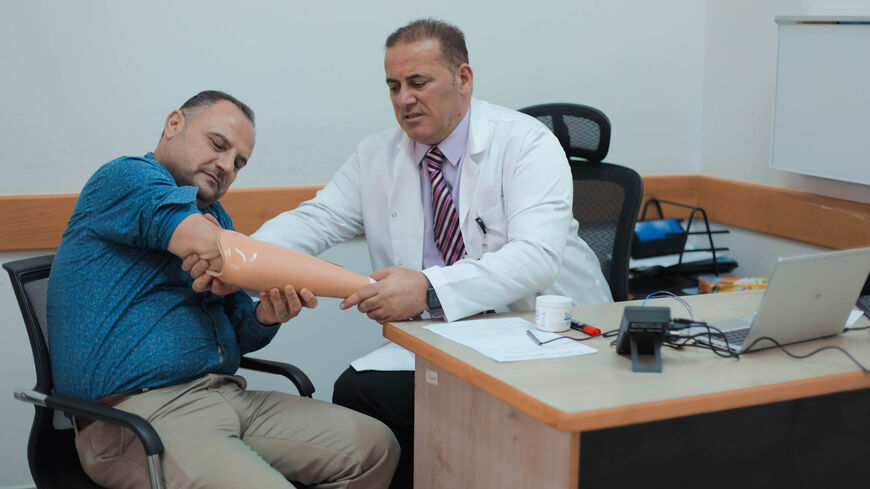 Dr. Omar Hafizah, head of the Prosthetics Department at Hamad Medical Corporation, who was accompanying the Qatari delegation during his visit to the hospital to install modern prosthetics, appears in the photo with the first person to receive the smart prosthesis, Aug. 3, 2021.