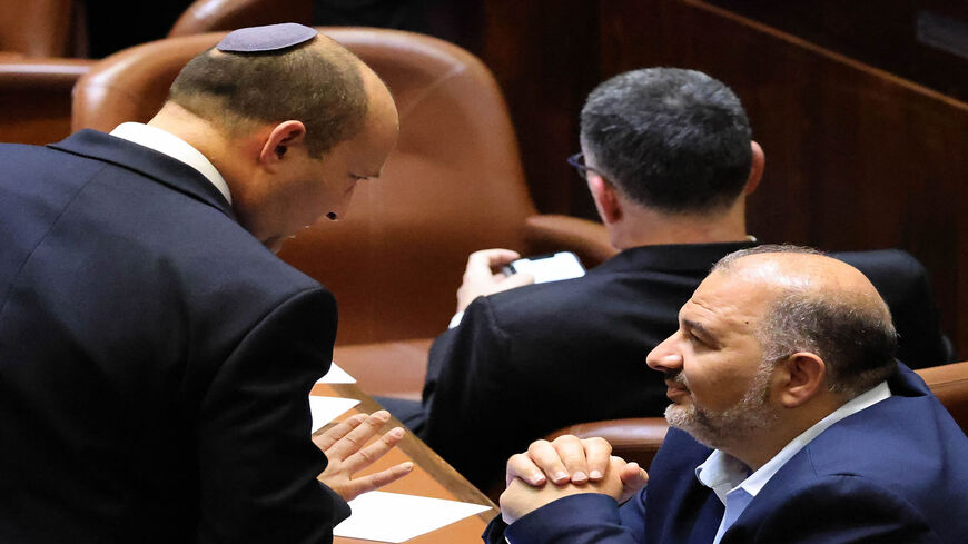 Head of Israel's right-wing Yamina party Naftali Bennett (L) chats with Mansour Abbas, head of the conservative Islamic Raam party, during a special session to vote on a new government at the Knesset, Jerusalem, June 13, 2021.