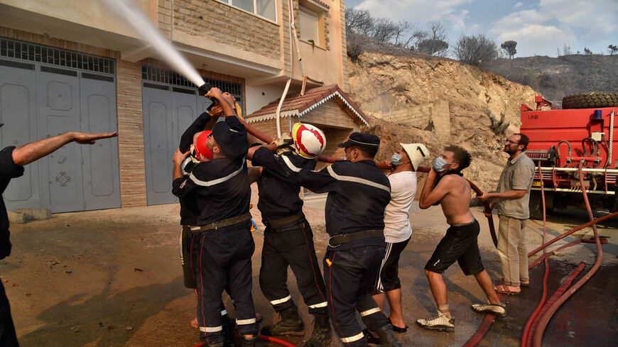 Firefighters battle the flames of a building on fire, in the forested hills of the Kabylia region, east of the capital Algiers, Algeria, Aug. 11, 2021.