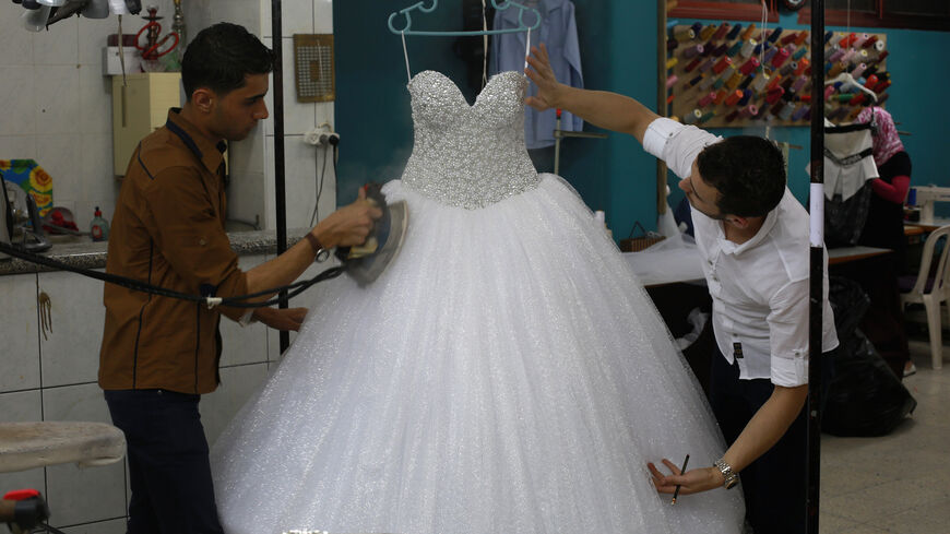 Palestinian designer from the al-Ashi family checks a wedding gown as it is being steamed at their atelier in Gaza City on June 3, 2013. 