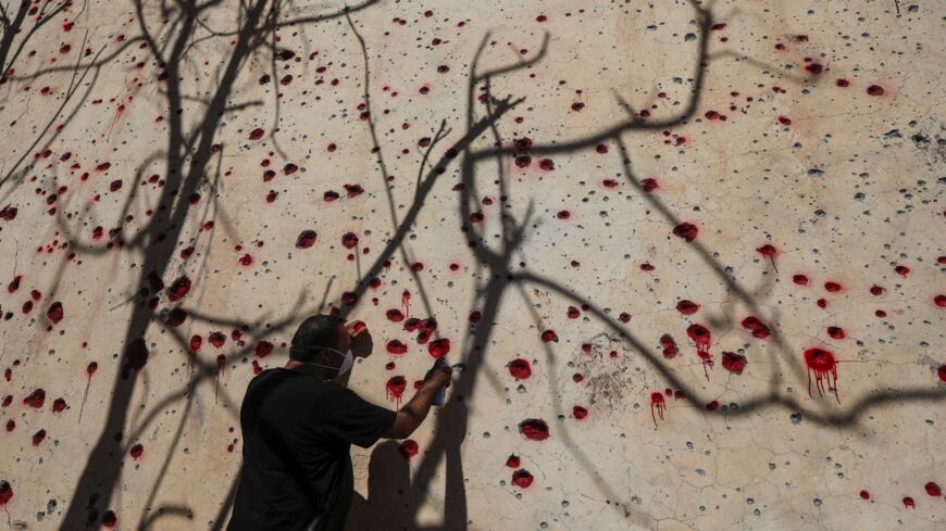 An Iranian Kurdish peshmerga member of the Kurdistan Democratic Party of Iran (KDPI) sprays red paint on holes in a wall made by shrapnel from a rocket attack days earlier.