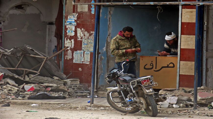 A Syrian man counts his money at a currency exchange counter in the town of Binnish in Syria's northwestern Idlib province, near the Turkish border, on March 6, 2020.