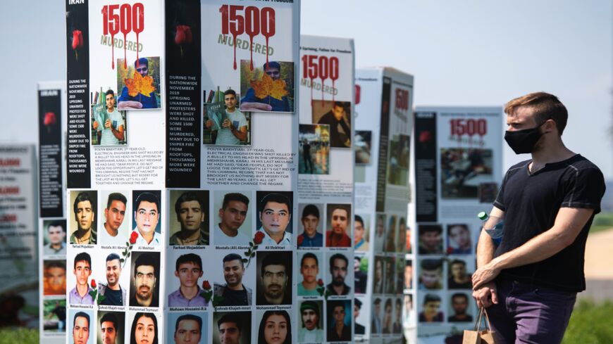 A man walks past some of the thousands of photos of people killed in Iran during the 1988 massacre of political prisoners.