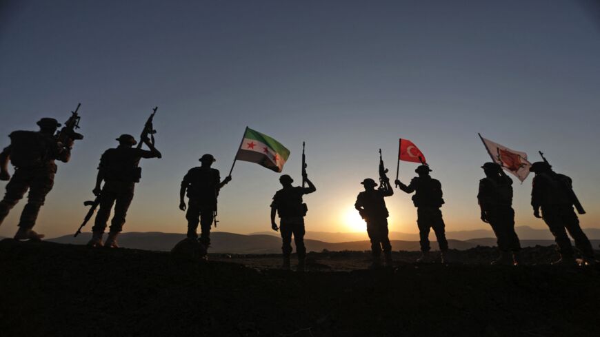 Turkish-backed Syrian fighters hold up the flags of (R to L) their unit, Turkey and the flag of the Syrian opposition.