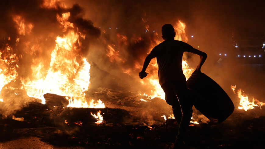 A Palestinian youth prepares to throw a tire onto a fire following a rally in support of Palestinian prisoners near the West Bank town of Nablus last week. Zakaria Zubeidi, one of six Palestinians who broke out of Israel's Gilboa prison, was allegedly beaten after being recaptured Saturday. 