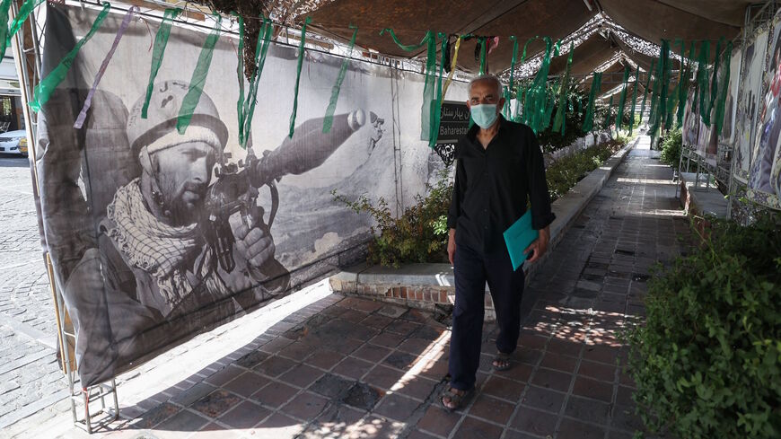 An Iranian man walks past banners at a street exhibition by Iran's army and paramilitary Revolutionary Guard force to celebrate "Defence Week", marking the 41th anniversary of the start of 1980-88 Iran-Iraq war, at the Baharestan Square in Tehran, on Sept. 25, 2021. 