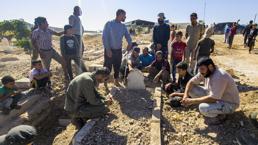 Mourners gather by the grave of one of fighters from the pro-Turkish "Hamza Division" Syrian rebel group killed in Russian air raids, at the Muhamadiya camp near Jindayris in the countryside of Aleppo in the Afrin region of northwestern Syria, on Sept. 26, 2021.  