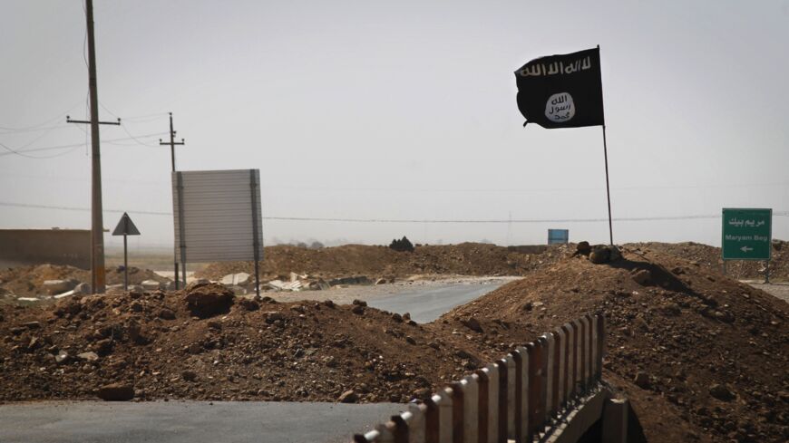 A flag of the Islamic State (IS) is seen on the other side of a bridge at the frontline of fighting between Kurdish peshmerga forces and Islamist militants in Rashad, on the road between Kirkuk and Tikrit, on Sept. 11, 2014. 