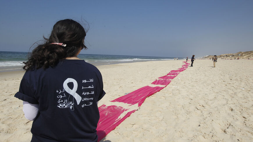 A Palestinian girl stands on a beach near a pink ribbon as part of the Breast Cancer Awareness campaign, Gaza City, Gaza Strip, Oct. 10, 2012.