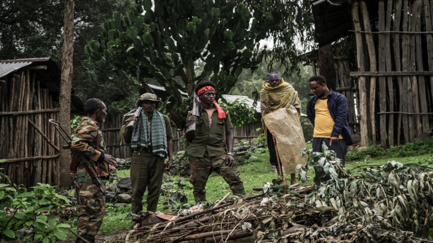 Amhara militiamen and villagers stand near a mass grave for victims killed in an alleged massacre in the village of Chenna in Ethiopia, on Sept. 14, 2021. 