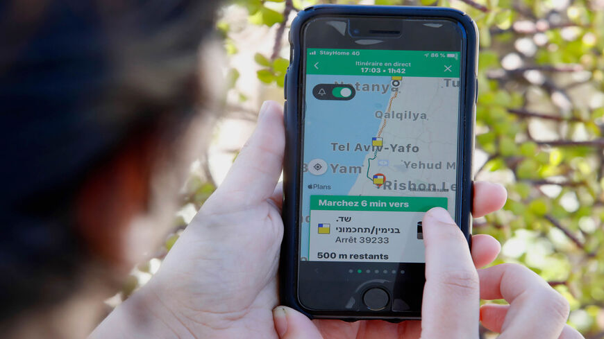 A woman checks on her cellphone the Moovit mobile transport application, Netanya, Israel, May 4, 2020.