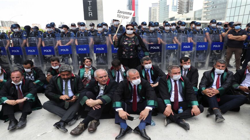 Senior lawyers protesting against a draft bill governing the organization of bar associations sit on the ground during a rally in front of Turkish riot policemen, in Ankara on June 22, 2020.