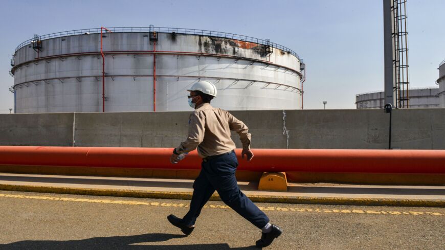 An employee at the Saudi Aramco oil facility walks near a damaged silo at the plant in Saudi Arabia's Red Sea city of Jeddah on Nov. 24, 2020.