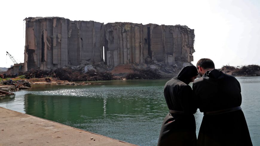 Maronite clergymen pray near damaged grain silos at the port of Lebanon's capital on Aug. 4, 2021.