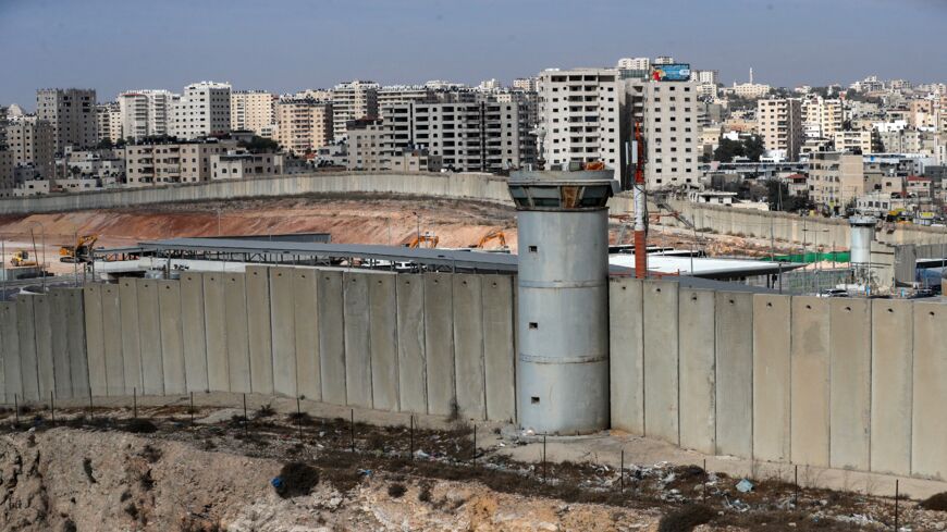 A general view shows a section of Israel's controversial separation wall (bottom) and machinery (L) working on the tarmac of the former Atarot Airport, Nov. 25, 2021.