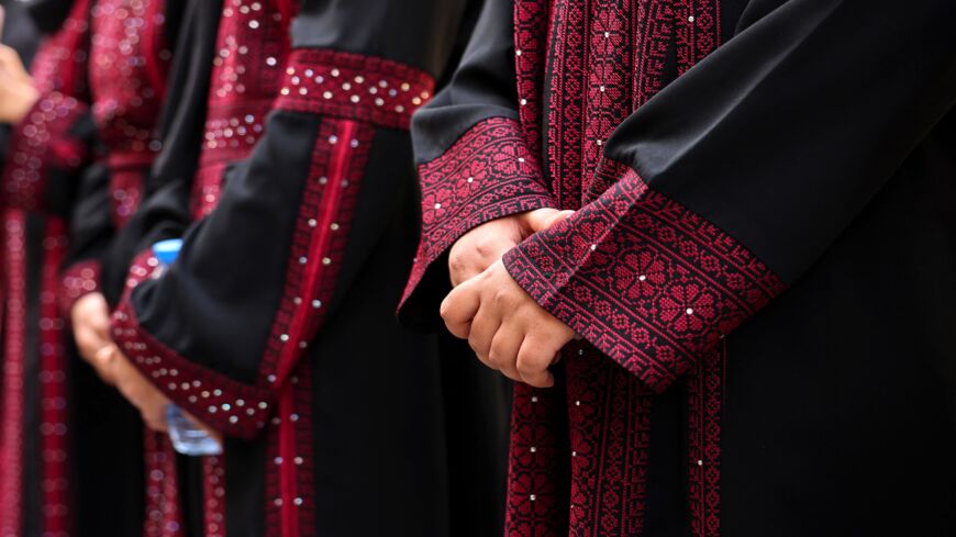 Palestinian university students wearing traditional embroidered dresses take part in an event entitled "Don't Steal Our Heritage" in Gaza City, on Dec. 16, 2021.  