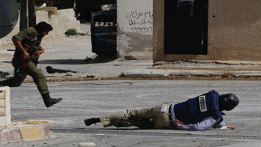 AFP reporter Sammy Ketz hits the ground as a Syrian soldier runs past during sniper fire in the ancient Christian Syrian town of Maalula, on Sept. 18, 2013. 