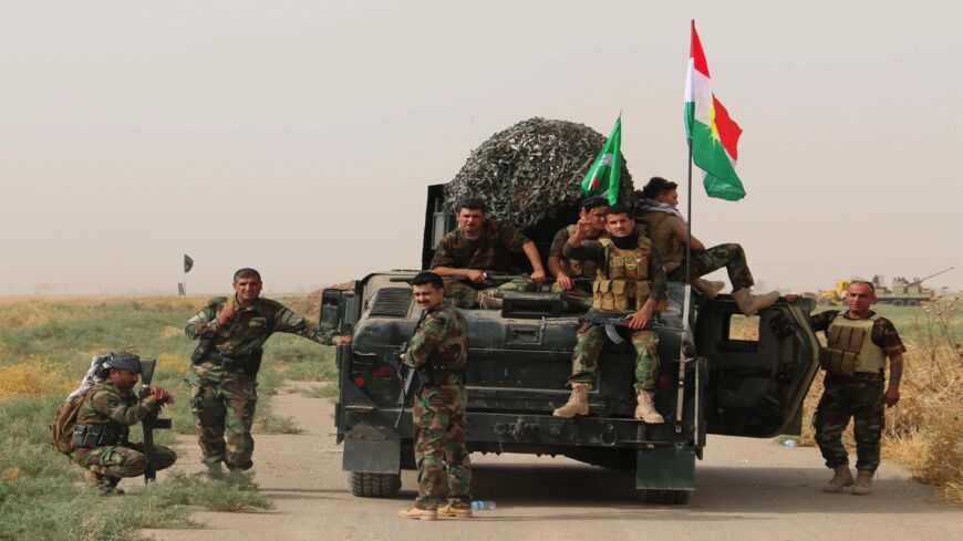 Iraqi Kurdish peshmerga fighters pose for a photo next to a military vehicle bearing the Kurdish flag after they reportedly captured several villages from the Islamic State in the district of Daquq on Sept. 11, 2015. 