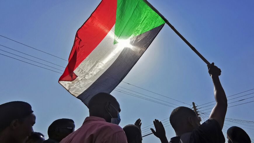 Sudanese protesters raise a national flag as they rally against the October 2021 military coup, in Khartoum on Jan. 13, 2022.