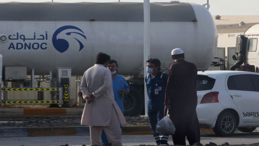 Men stand next to a tank at a storage facility of oil giant ADNOC in Abu Dhabi on Jan. 17, 2022.